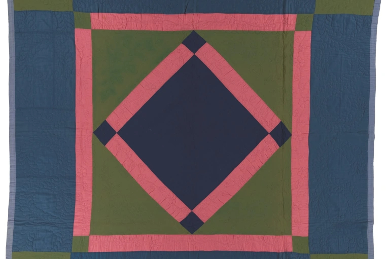 Navy and green quilt with red diamond in the center in the middle of a red bordered square