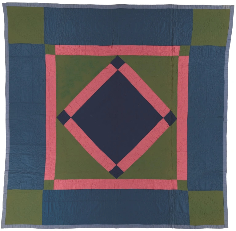 Navy and green quilt with red diamond in the center in the middle of a red bordered square