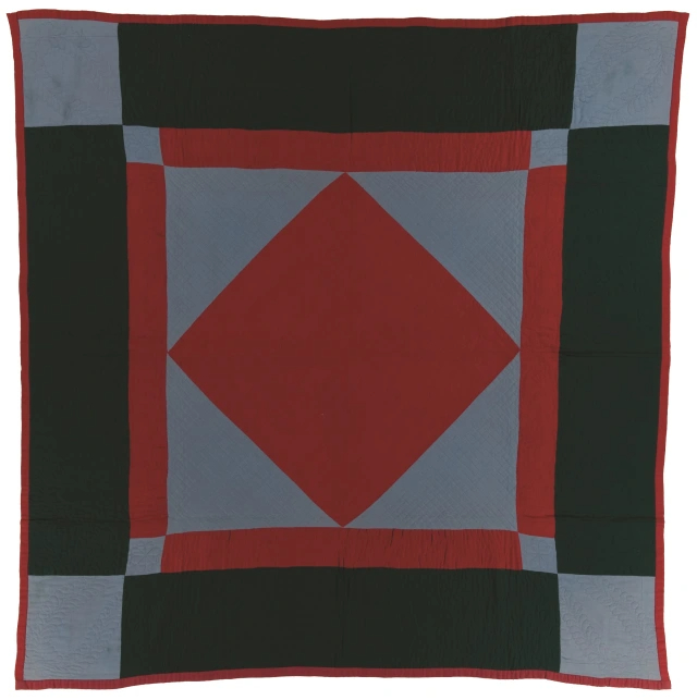 Rectangular quilt with wide dark green border, light blue squares at each corner. The centre design is made of a navy blue border with light blue corners with red diamond in the middle.