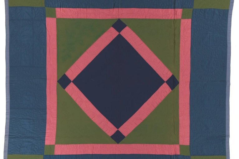 Navy and green quilt with red diamond in the center in the middle of a red bordered square