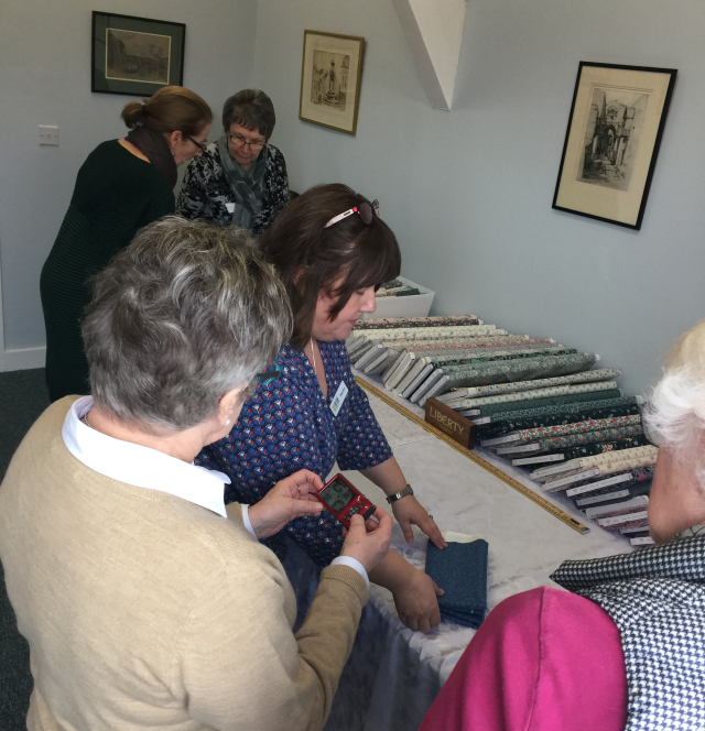 A group of women looking at a selection of fabrics for sale.