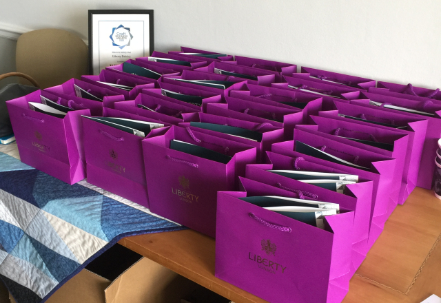A collection of pink Liberty gift bags in rows on a table.