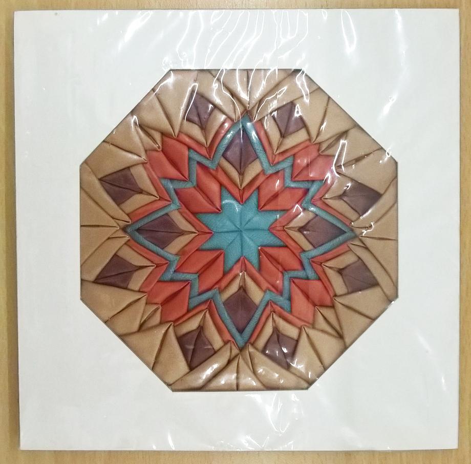 Motif showing the mitred patchwork technique - also known as the folded star - in brown, red and blue.