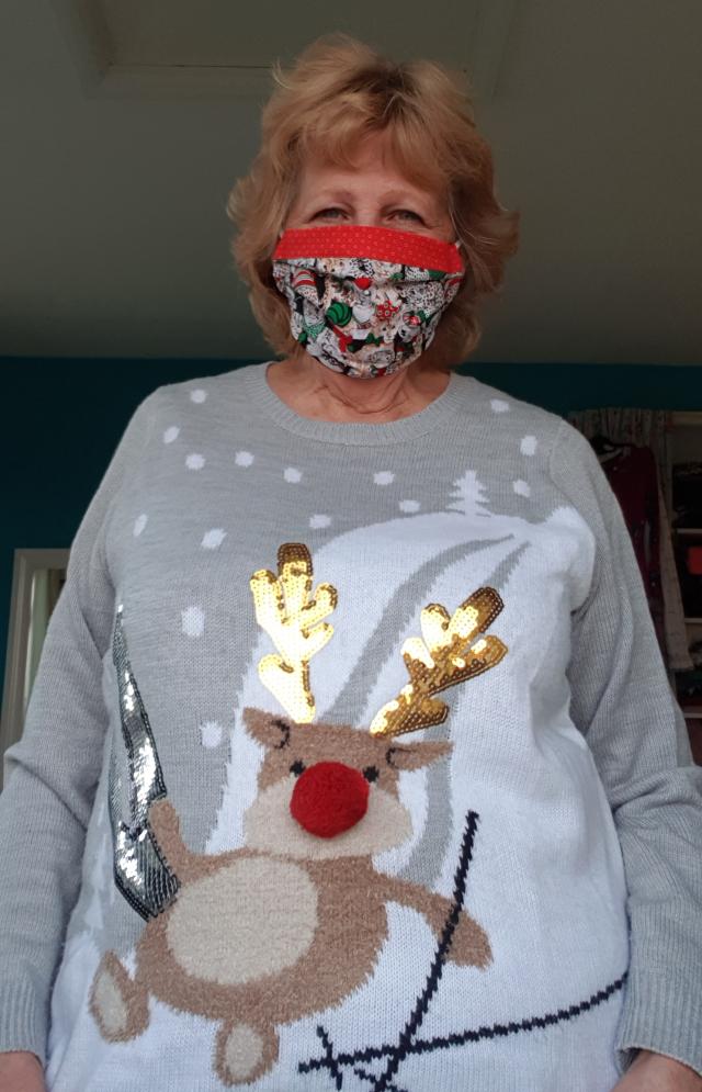 Moira Neal wearing a festive facemask and a Christmas jumper with a red nose reindeer and gold sequinned antlers