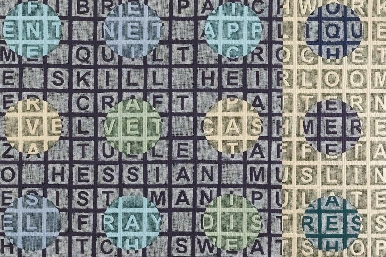 Quilt using different coloured fabrics with letters in the background and multiple circles in the foreground