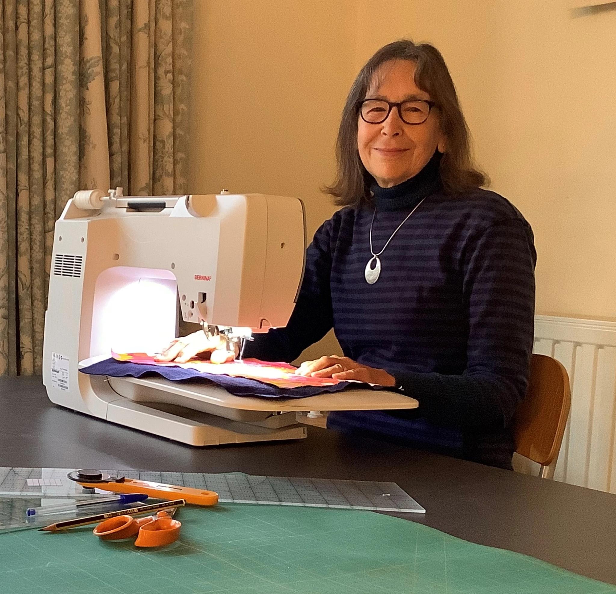 Sara Impey sat at a table working on a sewing machine