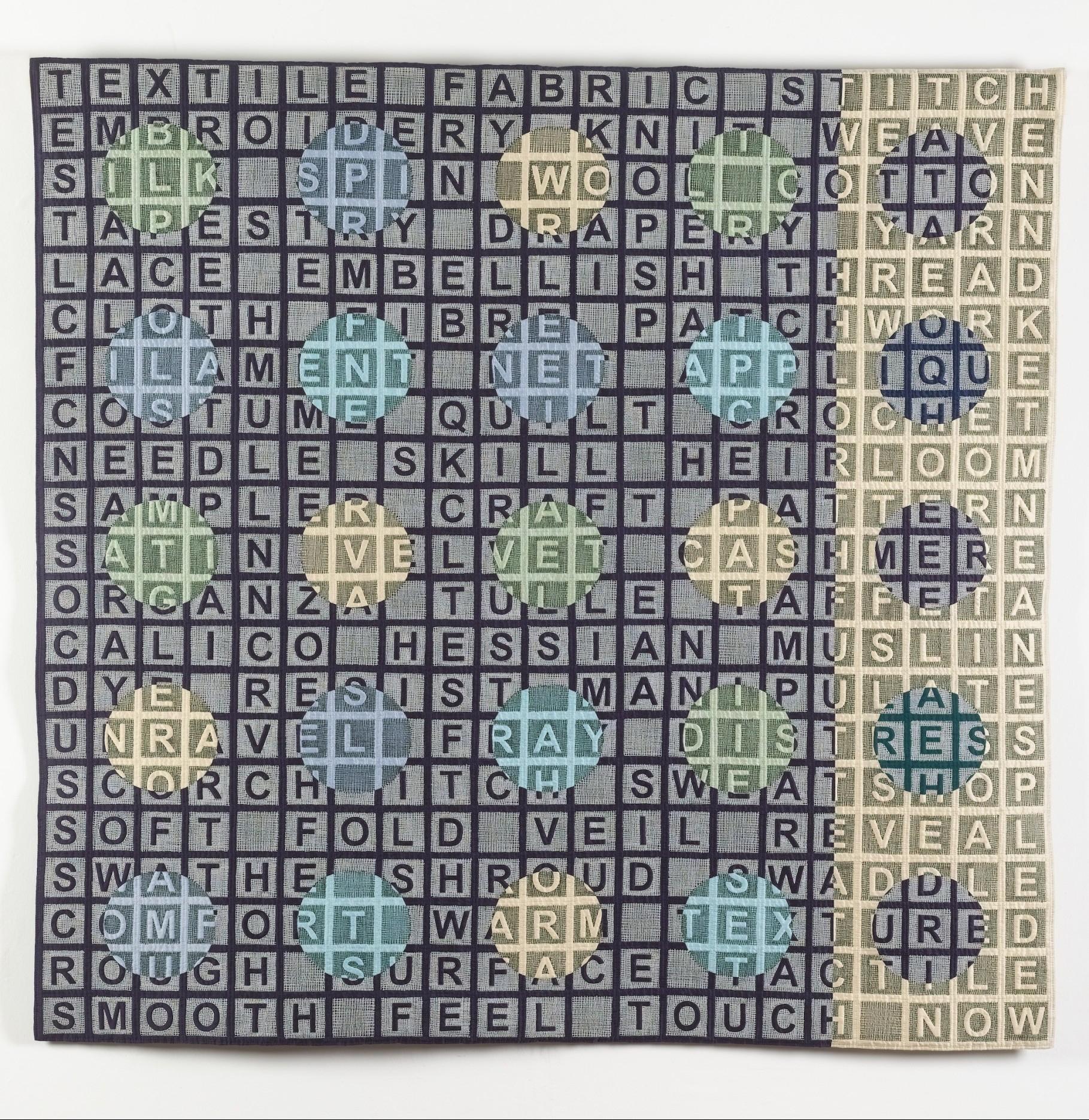 Quilt with a background made of a large square and rectangular with letters arranged like a crossword. Multiple circles in the foreground