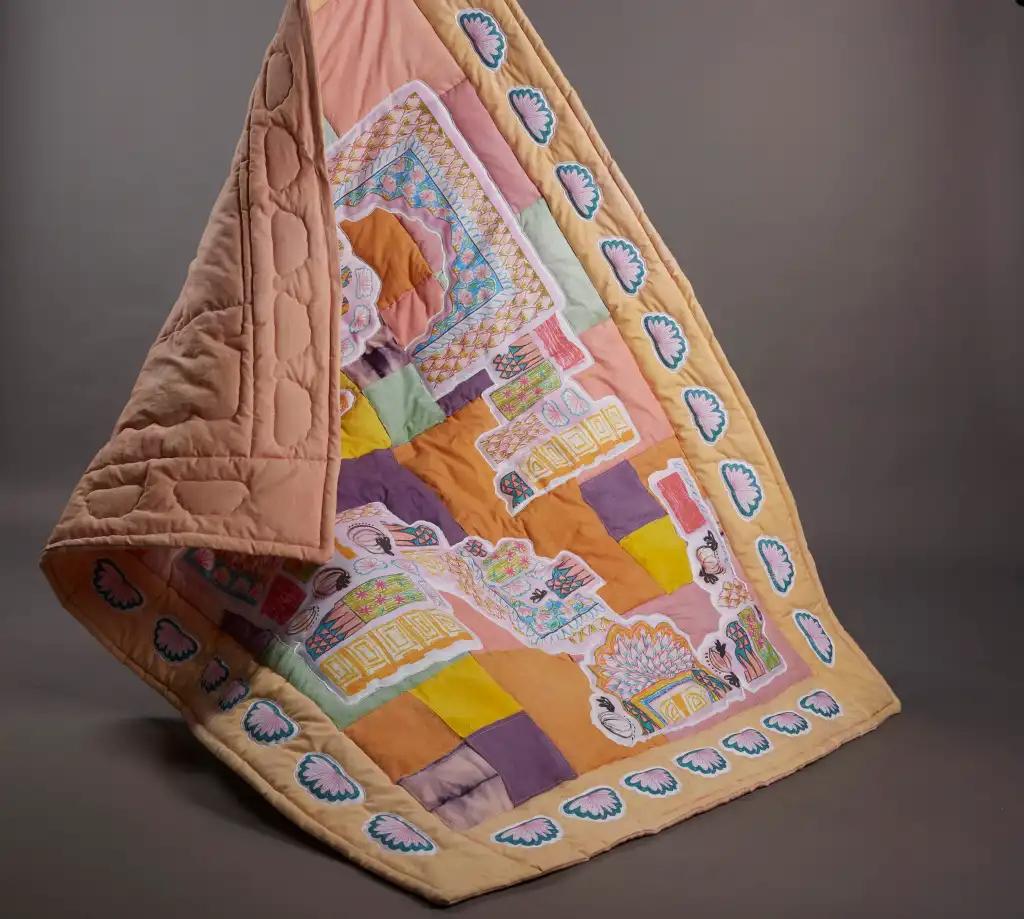 Small rectangular quilt with orange, yellow, pink and purple squares background and a design inspired by India stitched on top