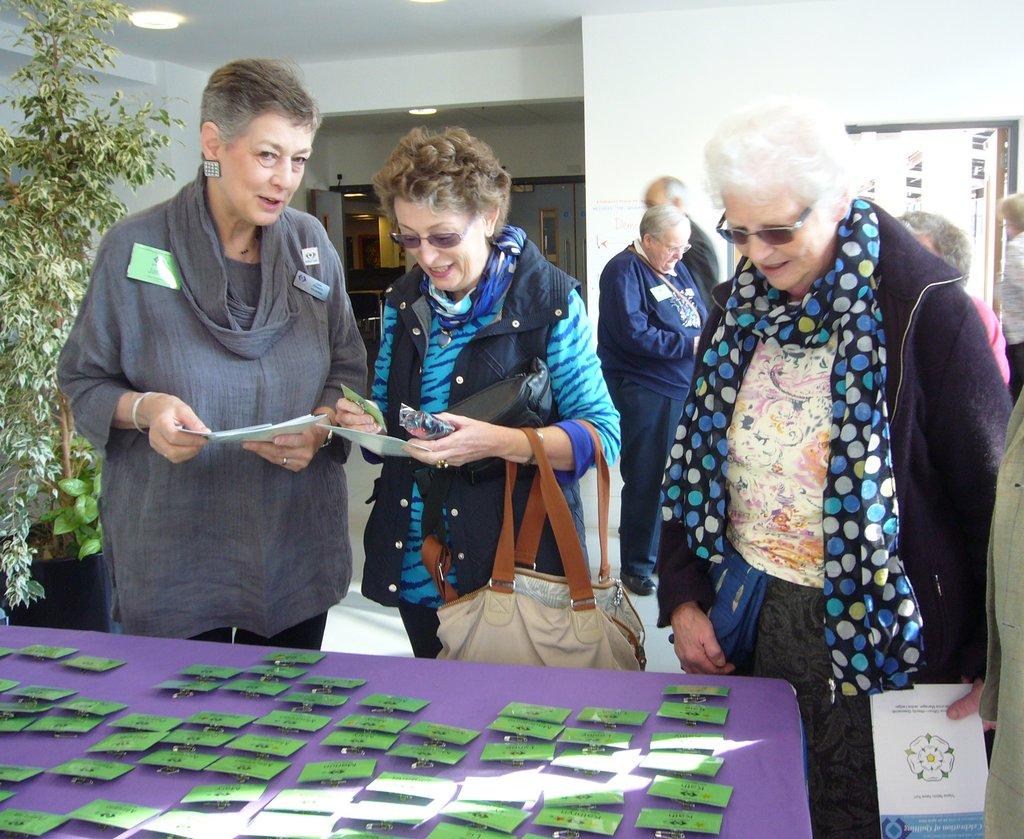 Members attending conference collecting name badges from a table.