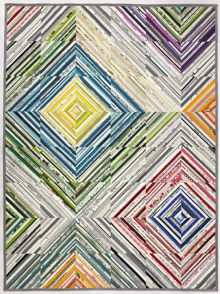 Quilt made of small squares of diagonal multicoloured lines.
