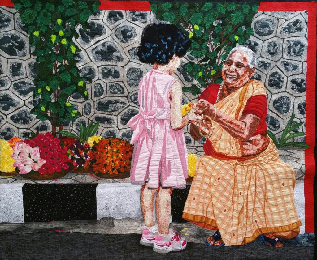 Quilt depicting a child greeting an old lady wearing a sari sat on a wall