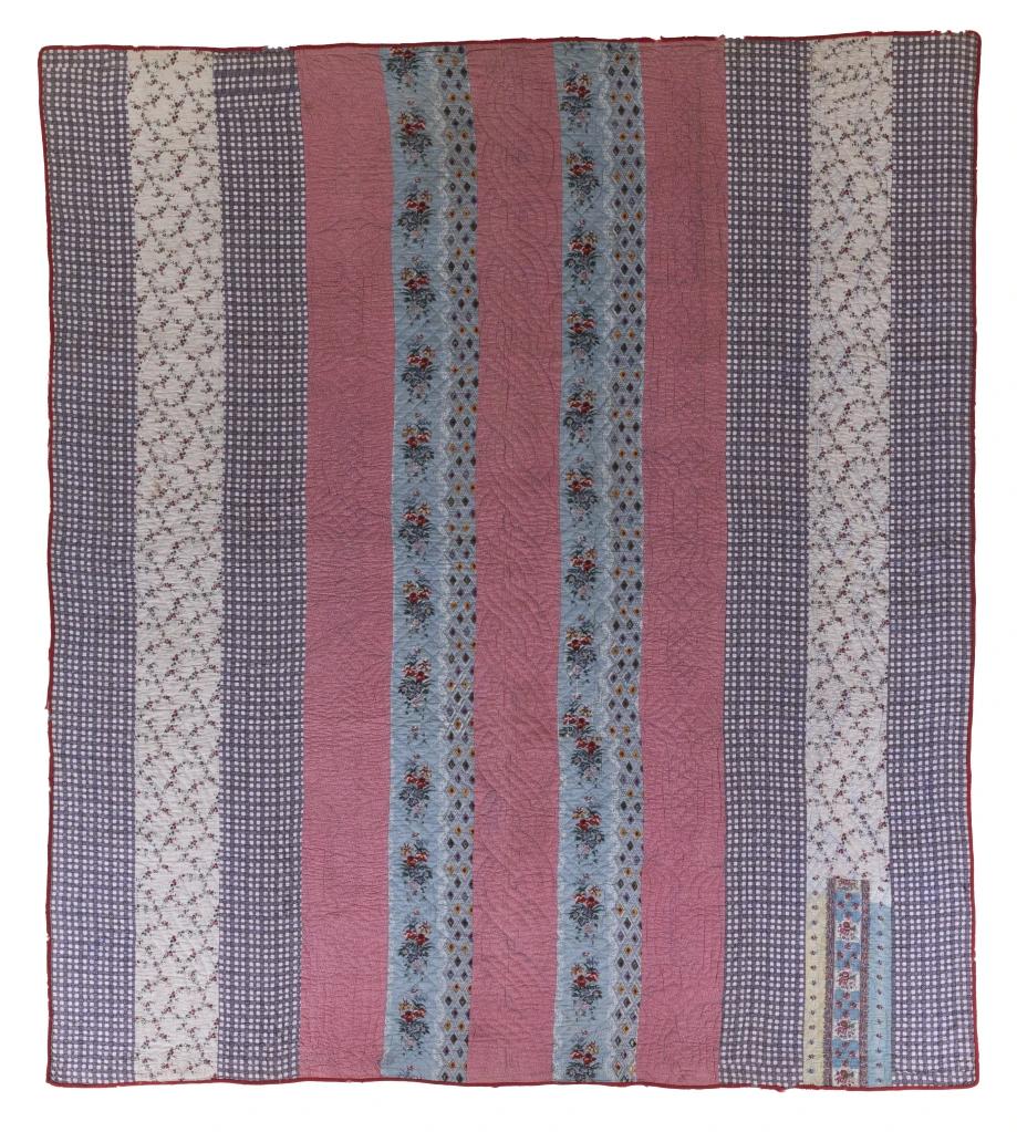 Quilt made of vertical stripes in alternating patterned fabrics: blue gingham, white floral, red, blue with flowers