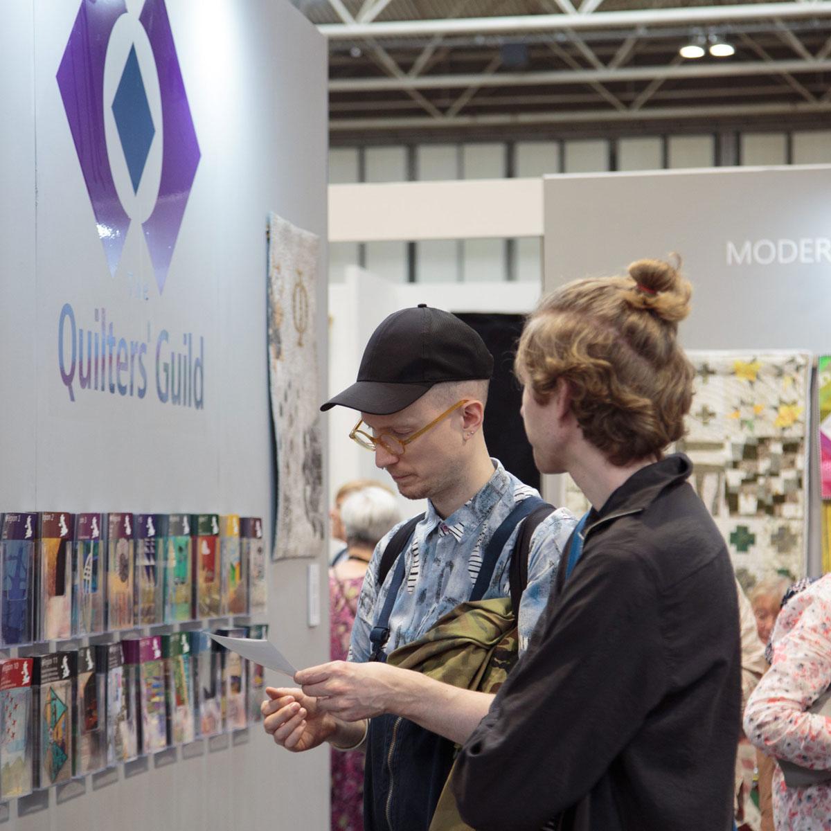 Two people looking at leaflets on the Quilters' Guild stand