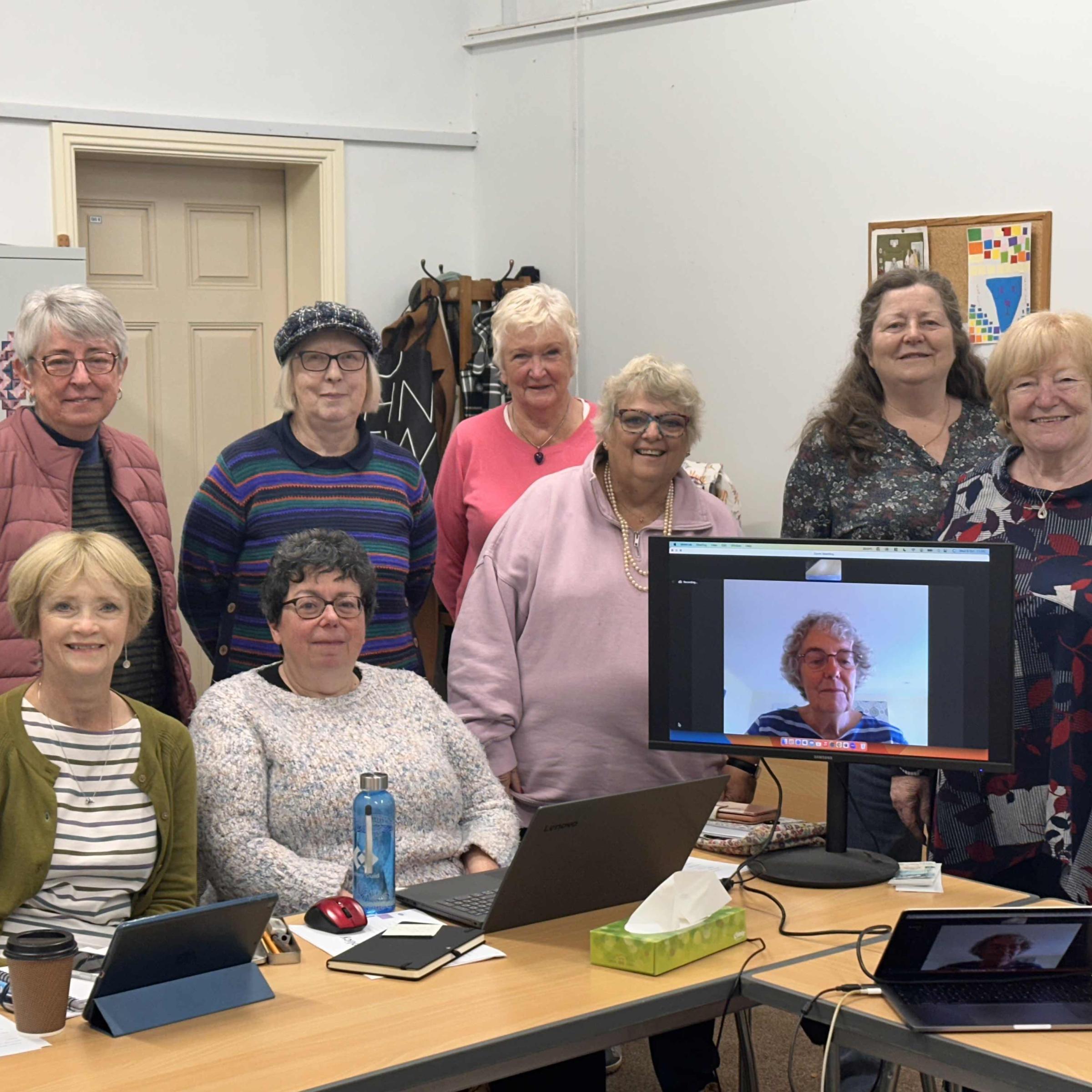 Quilters Guild trustees, a group of ladies stood behind a computer monitor