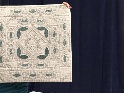 Beige and green quilt with semi-circles and floral pattern