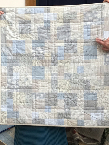 Quilt with square and rectangular blocks using pale blues, greys and beige.