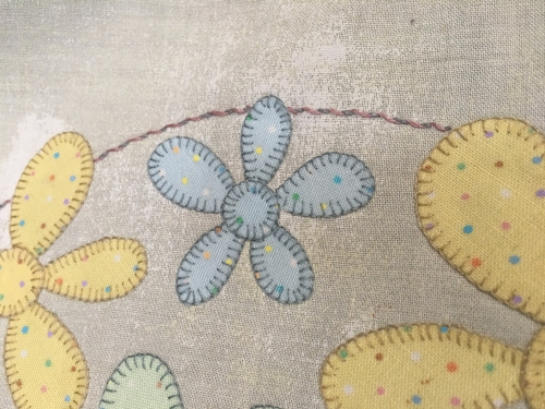 Close up detail of coloured flowers sewn on beige fabric