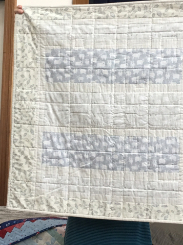 Quilt with square and rectangular blocks using pale blues, greys and beige.