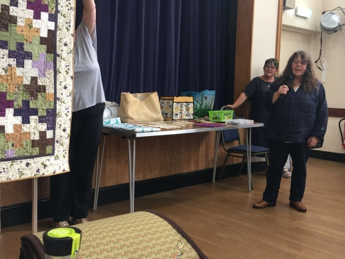 Woman talking into microphone stood next to a table