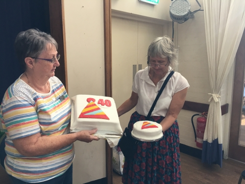 Two ladies holding up birthday cakes
