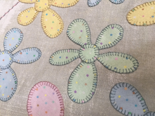 Close up detail of coloured flowers sewn on beige fabric