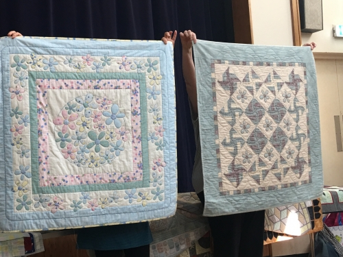 Two quilts. One with pink, blue and yellow floral pattern and one with blue, beige and burgandy windmill pattern