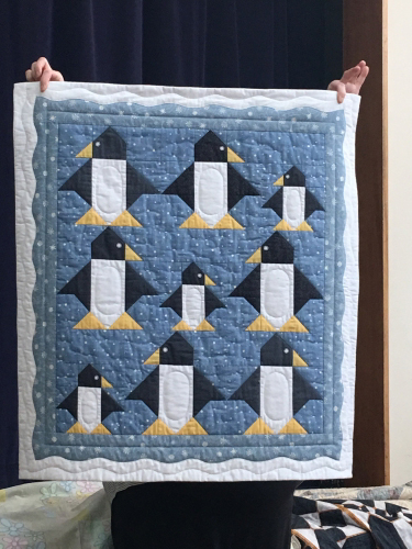 Quilt with geometric style penguins on a blue background
