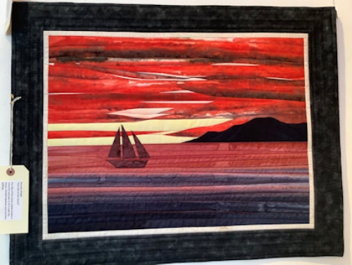 Quilt depicted a sailing boat on water at sunset