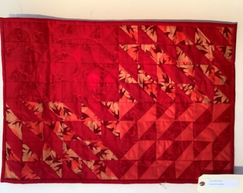 Quilt with repeated pattern of triangles in 5 different red fabrics