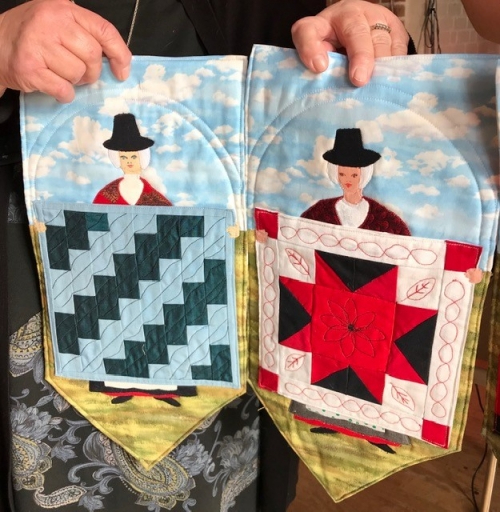 2 small mini banners depicting traditional welsh ladies holding a quilt