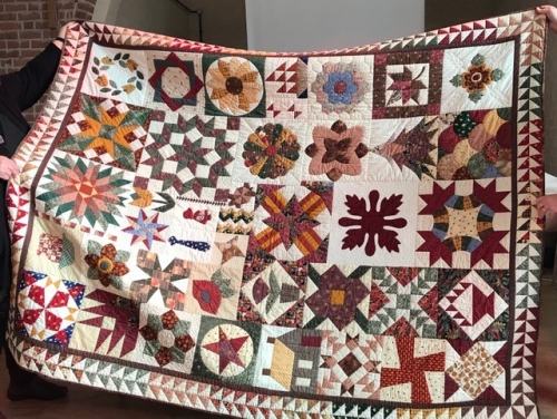 Traditional sampler quilt using burgundies, greens and oranges