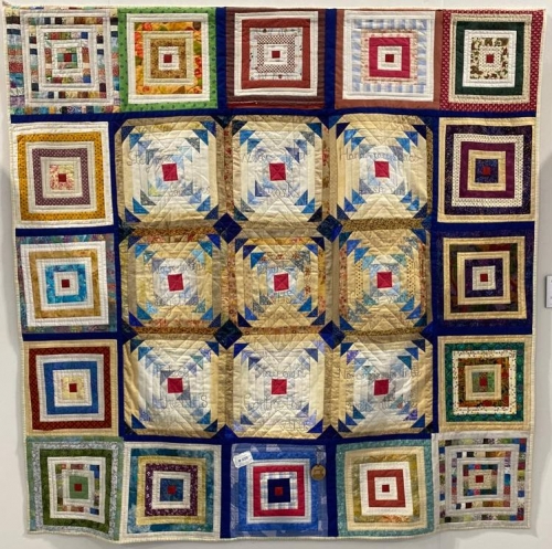 Mulit-coloured quilt with repeated blocks of concentric squares and triangles