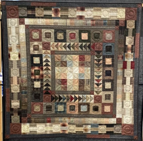 Traditional quilt with repeated pattern in beige, browns and neutral colours