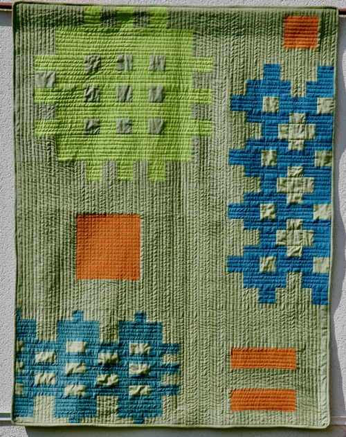 Sage green quilt with orange, blue and lime green pattern blocks