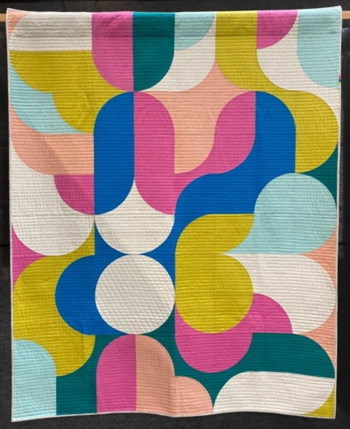 Quilt using greens, blues, yellows, pinks and off-white colours in a mid-century modern pattern