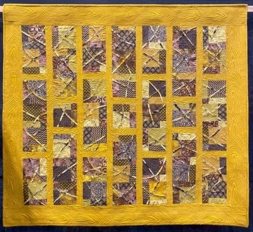 Golden yellow quilt with greys and browns and purples rectangular patterns