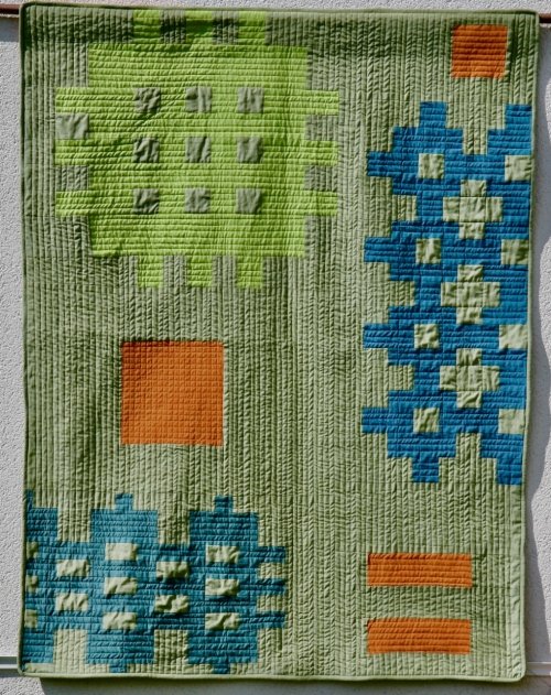 Sage green quilt with orange, blue and lime green pattern blocks
