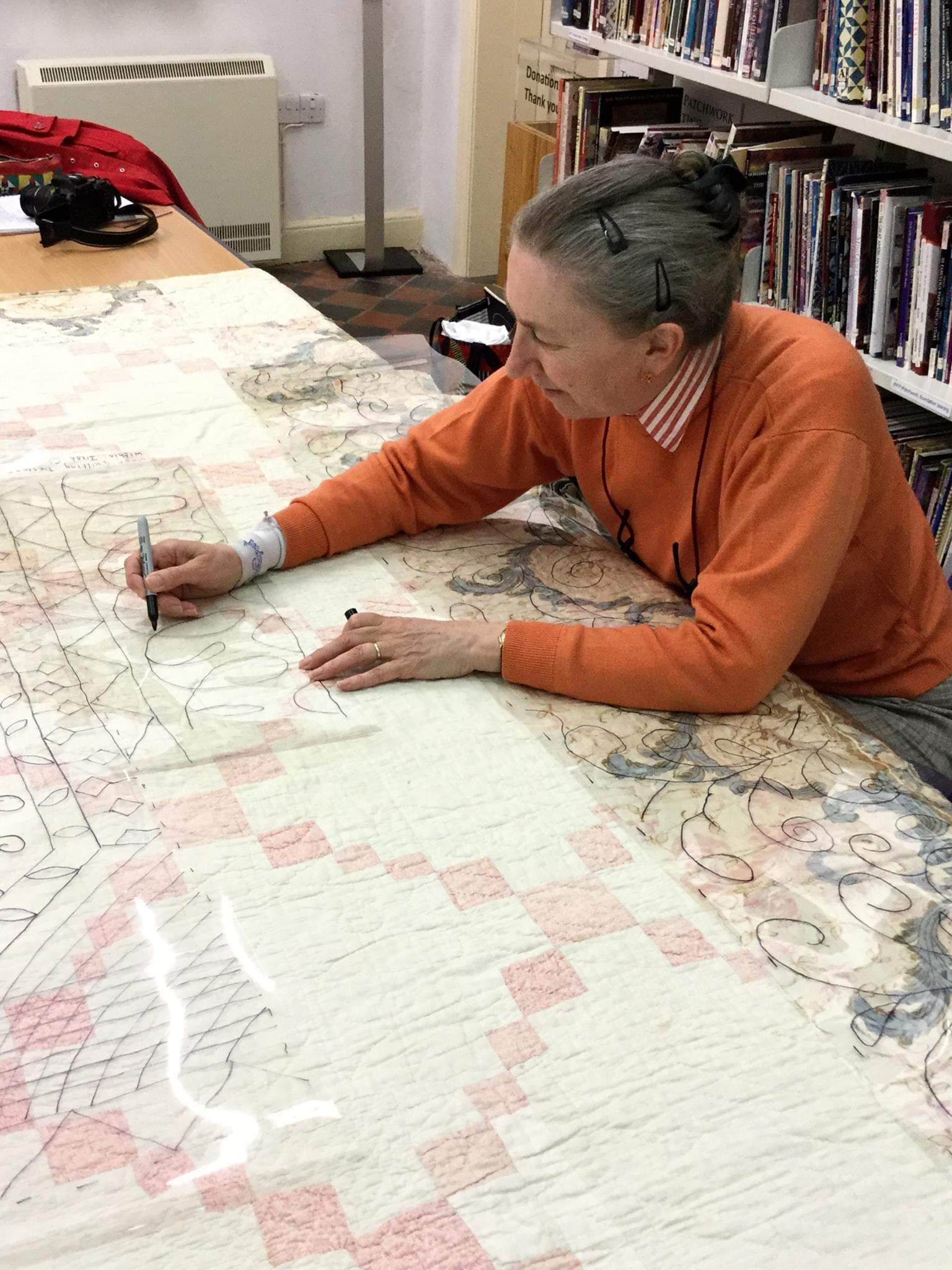 Woman tracing quilting design from an early quilt