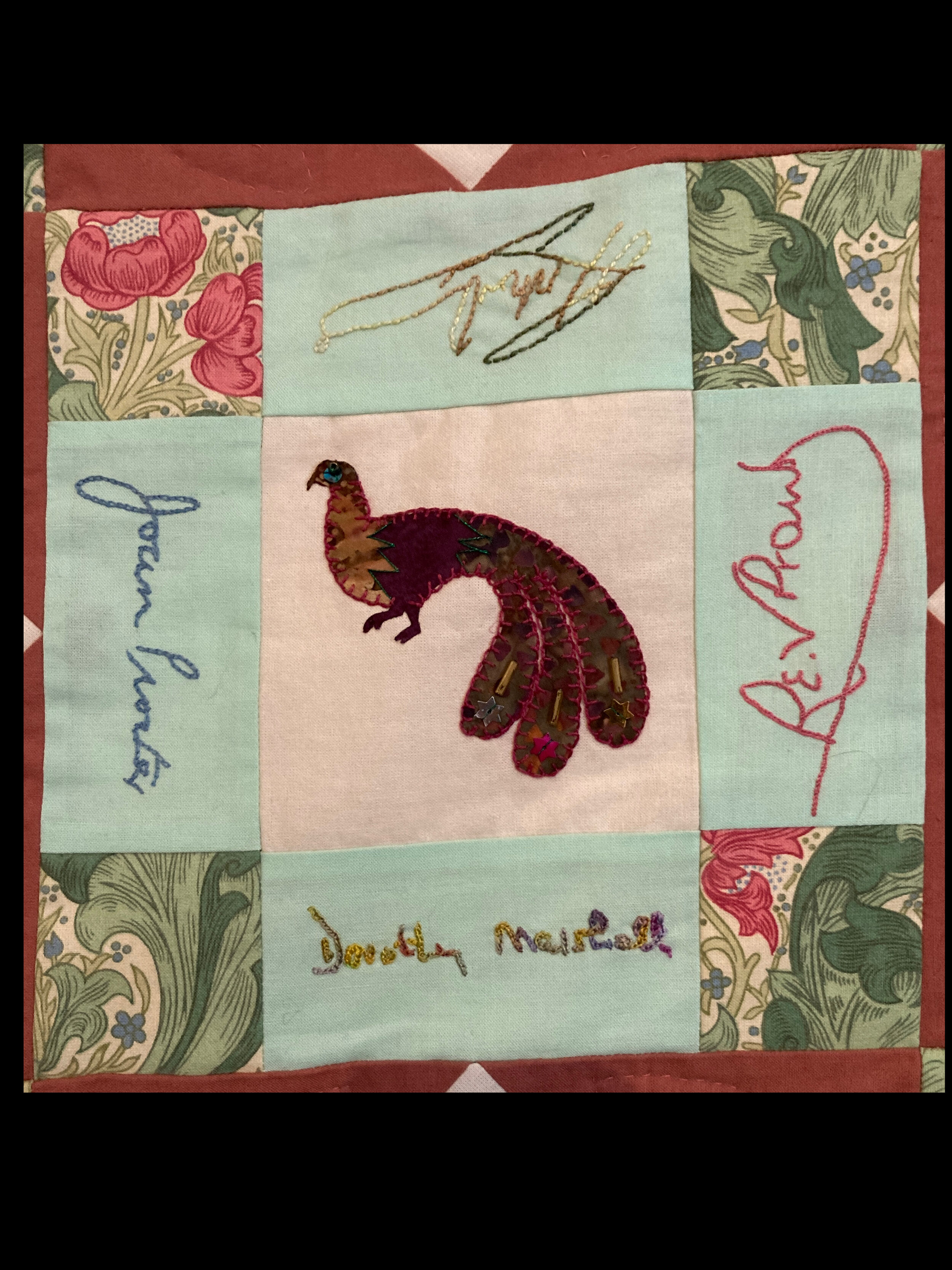 Peacock applique centre on a nine patch with signatures around it.
