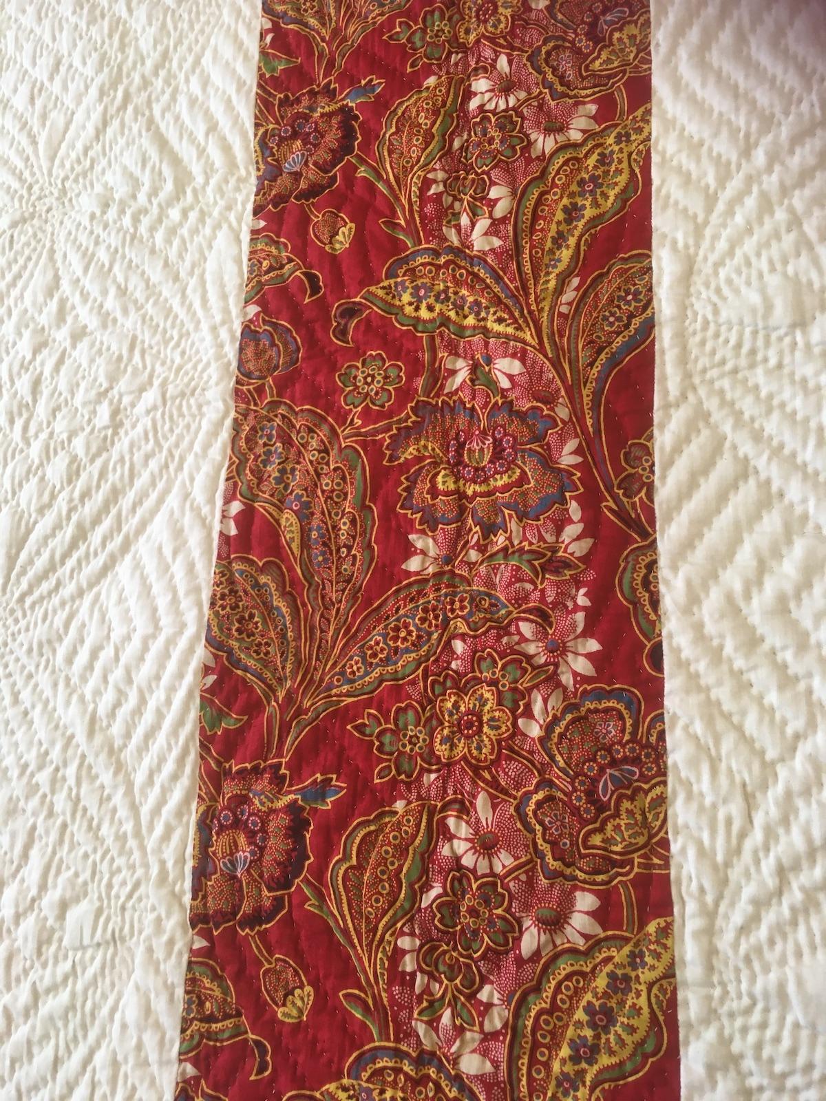 Bright red fabric with large floral design in blue, green, yellow and white.