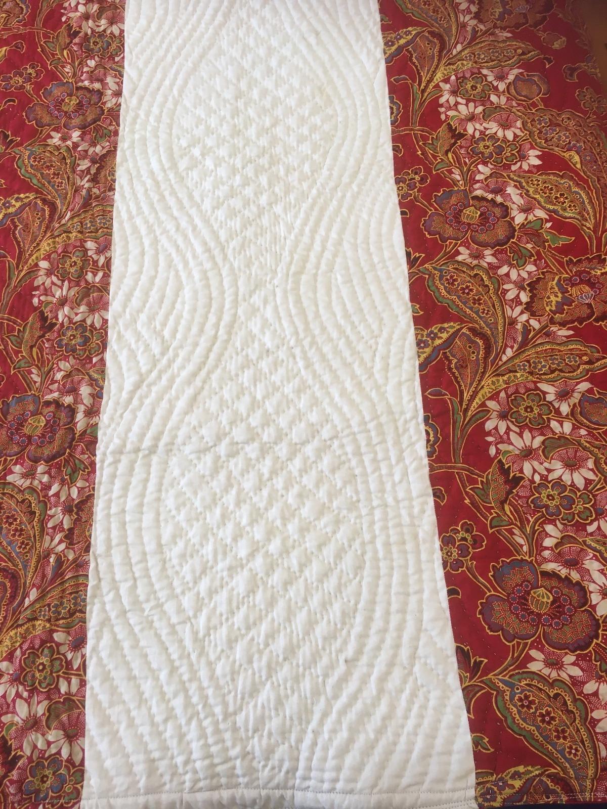 Hand quilting design of mirrored waving lines filled with grid