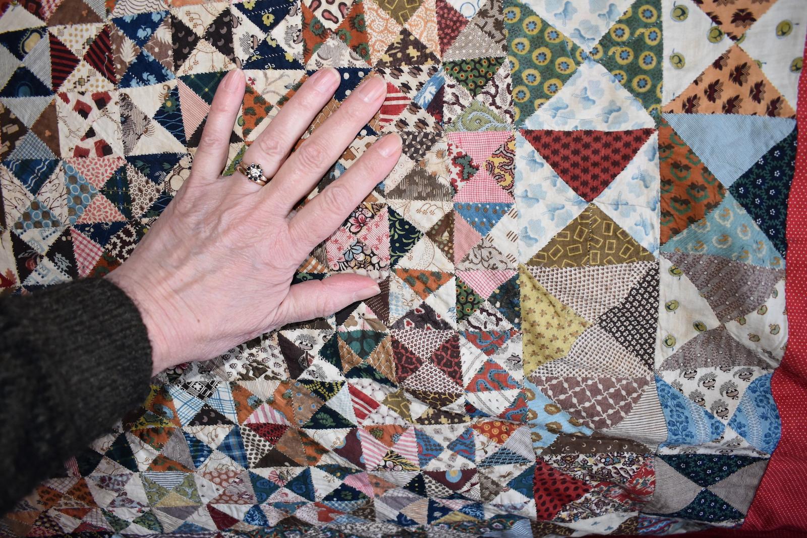 Patchwork with hand covering many triangles to demonstrate very small size.