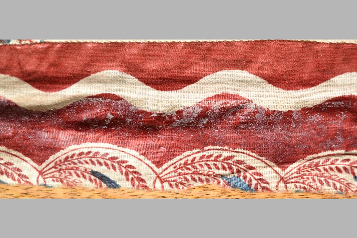 Fabric showing red fabric with leafy edge design
