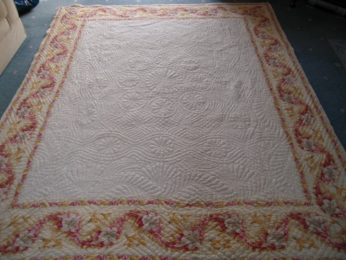 Off white coloured quilt with pink and yellow border pattern
