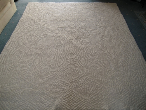 Back of a large off-white embroidered quilt