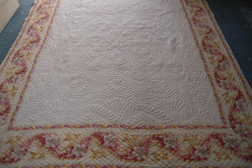 Off white coloured quilt with pink and yellow border pattern