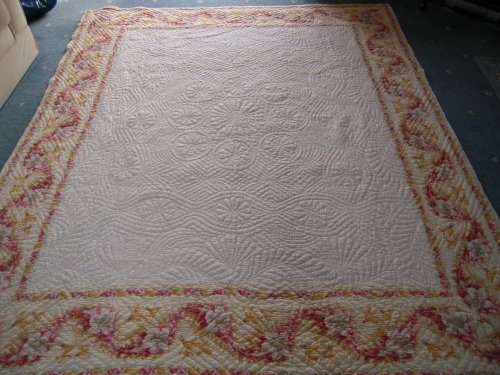 Off white coloured quilt with pink and yellow border pattern