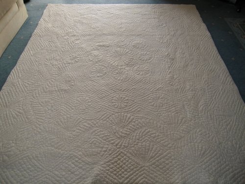 Back of a large off-white embroidered quilt