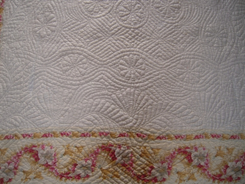 Close up of embroidered pattern on quite showing bellows, running feather and fans