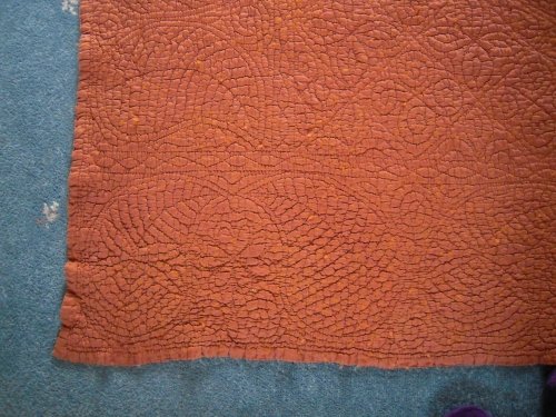 Close up showing corner stitching of rust coloured welsh quilt